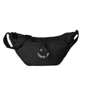 Black sling bag shown from the front with zippers and partial white circular text on the front pocket.